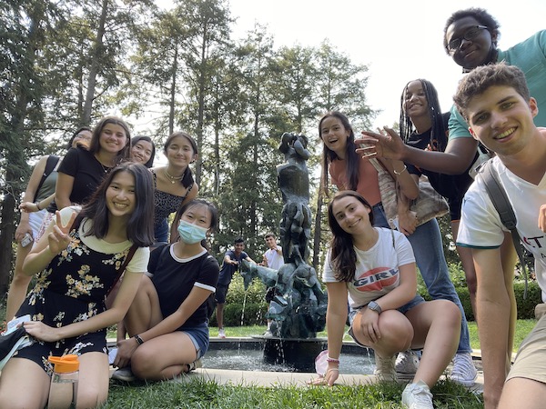 Group of students posing around statue