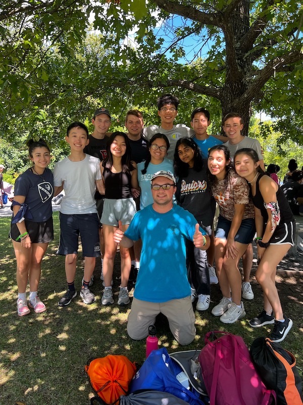 Students and man posing for group picture in front of tree