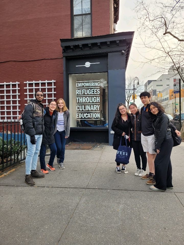 5 students posing for a photo in front of a restaurant
