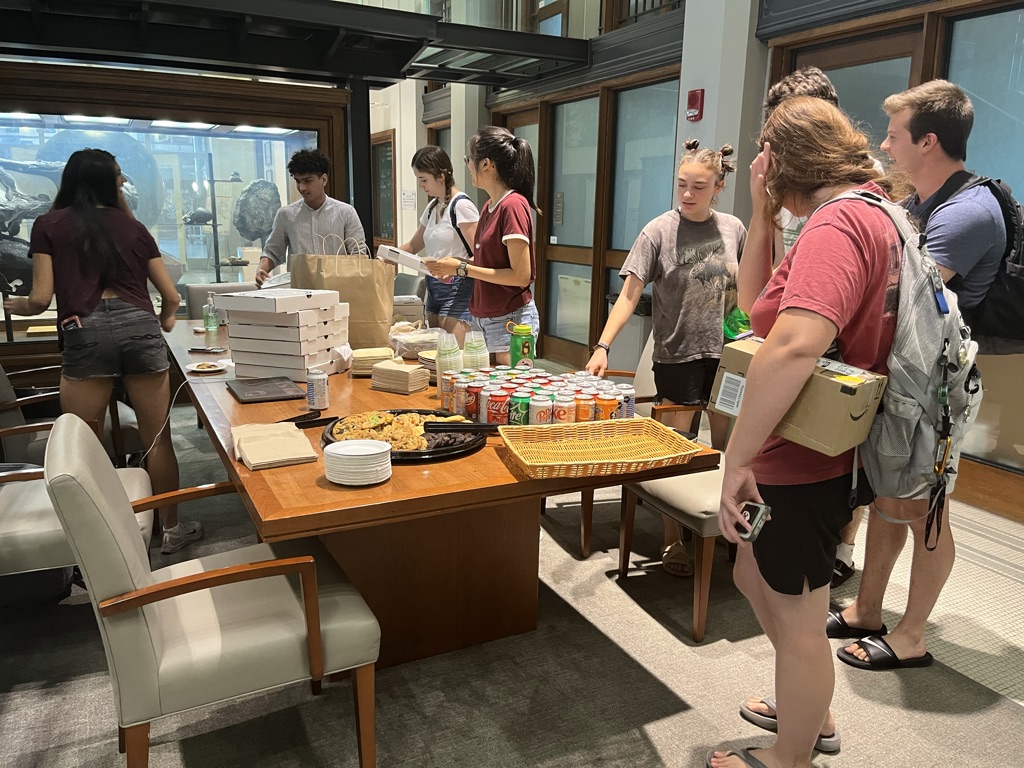 Students serving themselves pizza and soft drinks at a table inside Guyot Hall