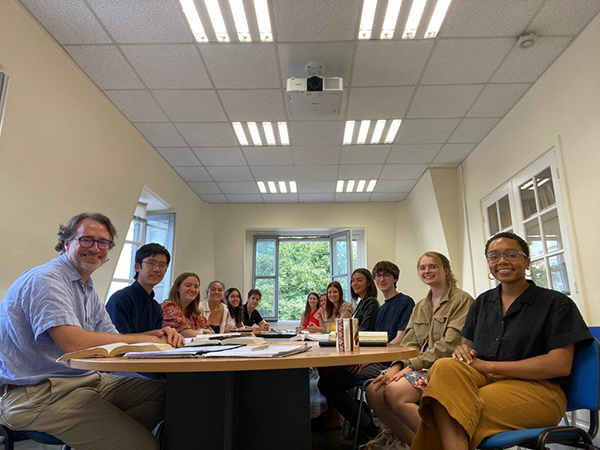 Class photo of students and professors sitting around a long table 