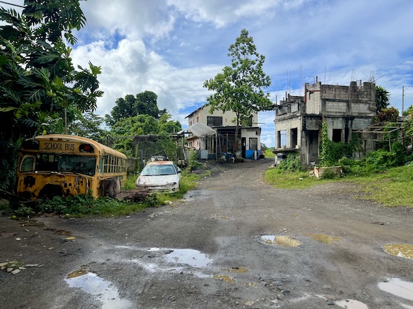 Parking lot with broken school bus and low-rise building in the El Yunque rainfores