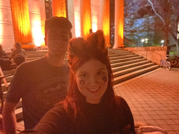 Two students outside of an orange illuminated Whig 