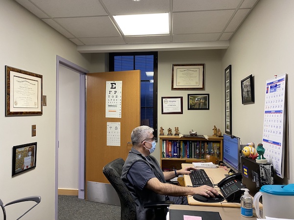 Image of a psychiatrist in an office, typing on a computer. 