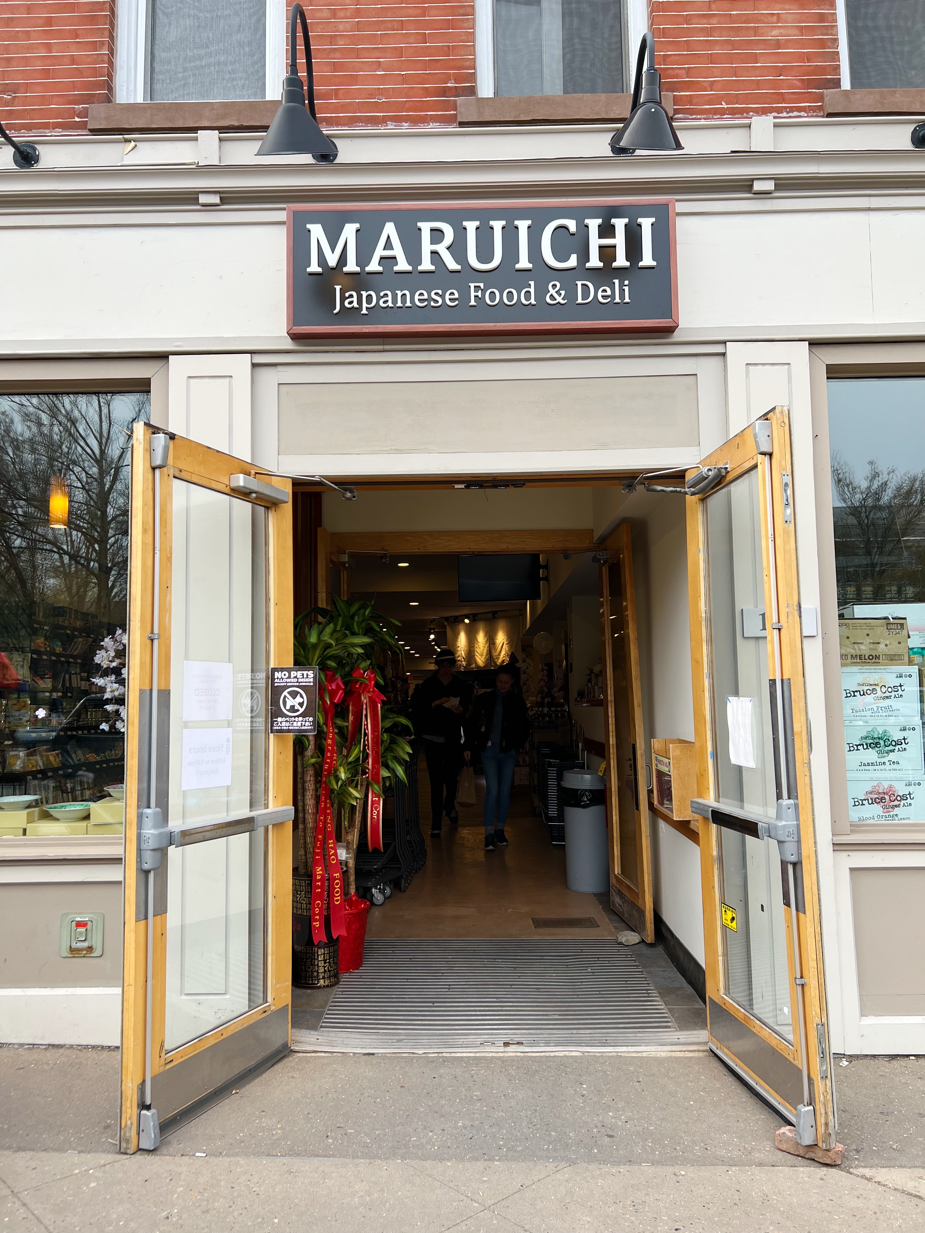 Exterior of Maruichi, white and brick building with double doors and sign above the doors