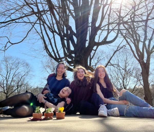 Four Princeton students laughing in front of trees and a blue sky.