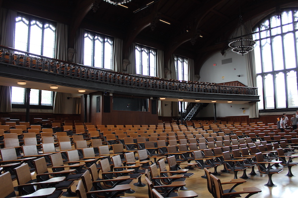large lecture hall with wooden seats and large chandeliers