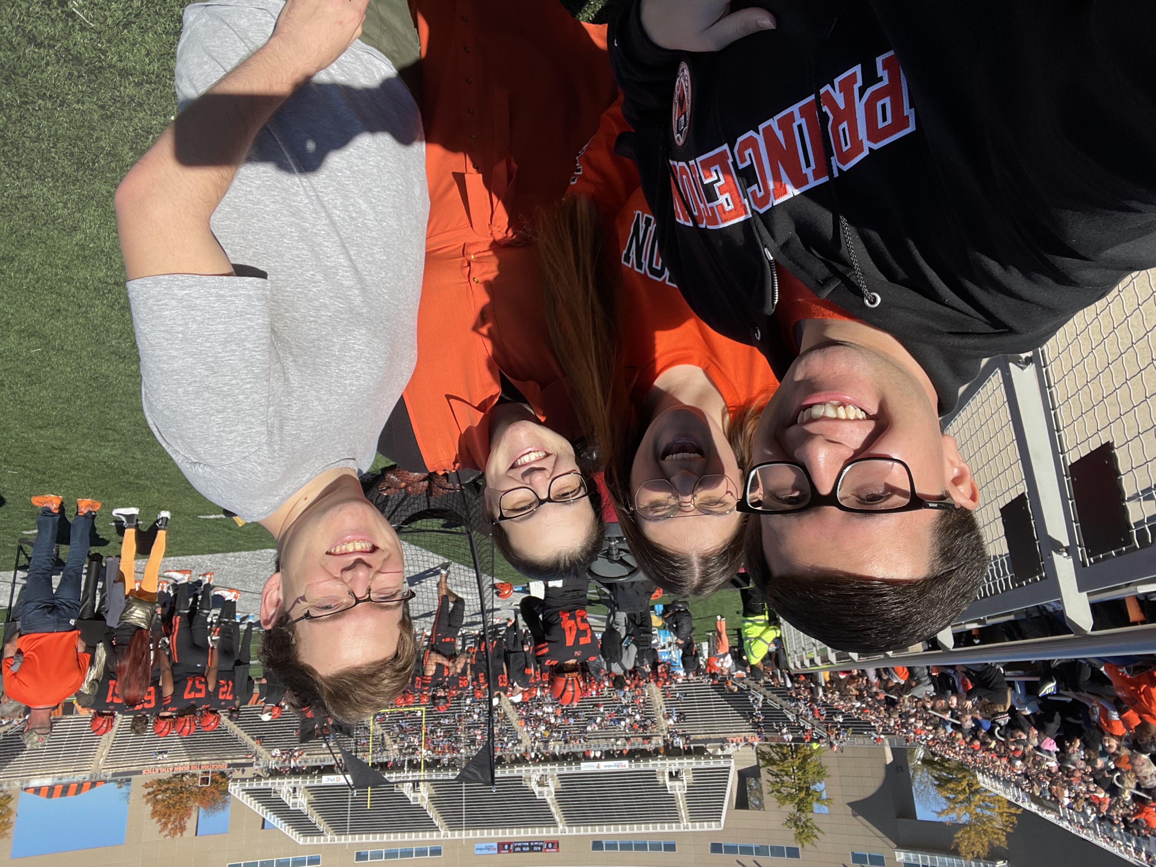 four people pose for a selfie on the field at Princeton Football game