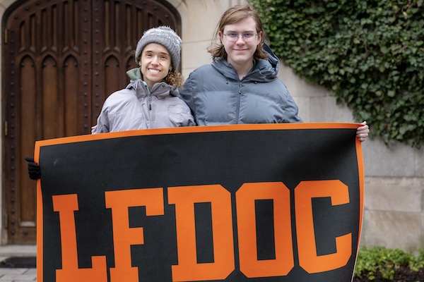 Two students dressed in winter gear holding LFDOC banner