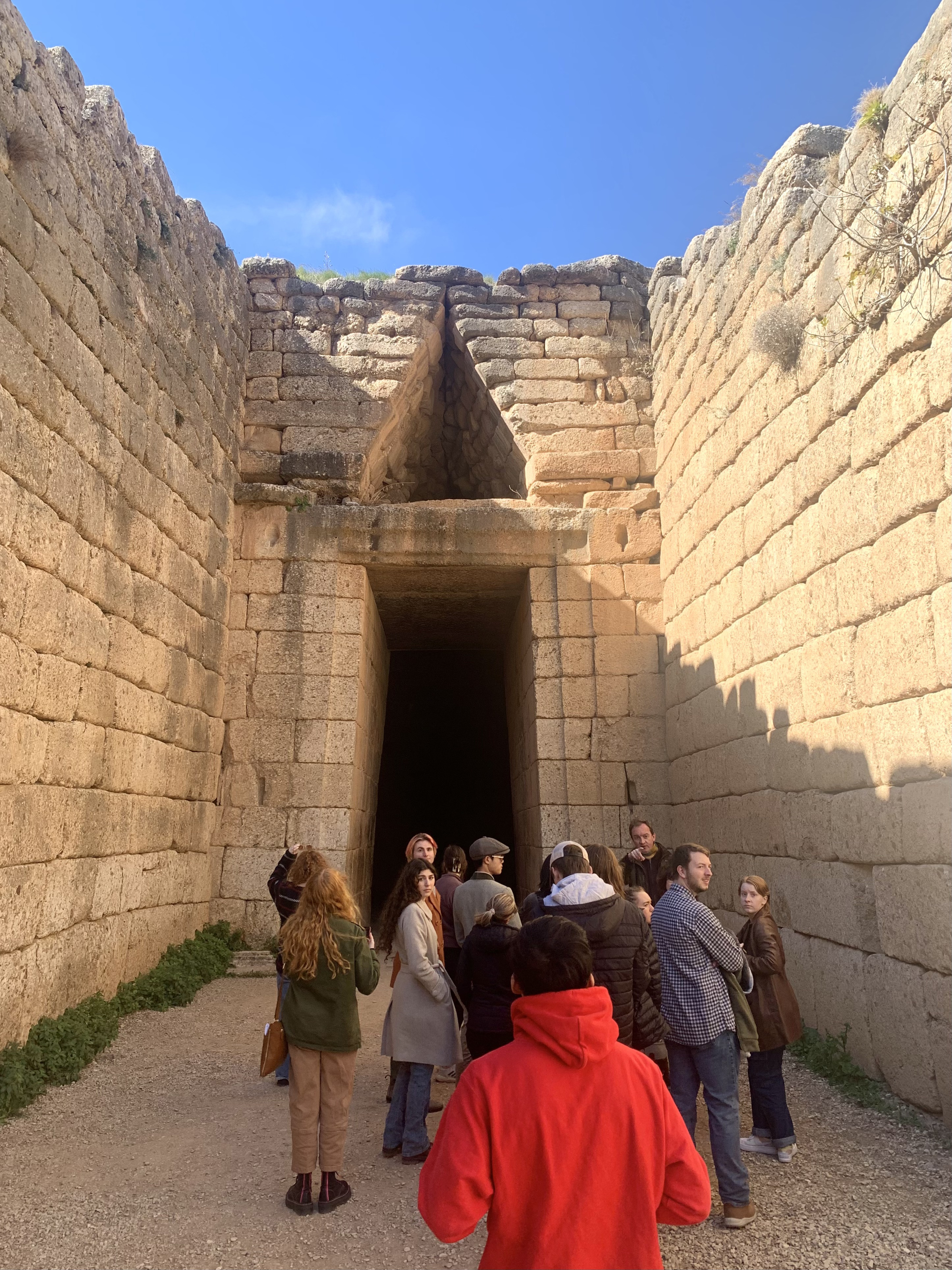 Group of students gather looking upward in subterranean, open-air stone ruin