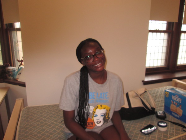 A girl sitting atop a stripped bed