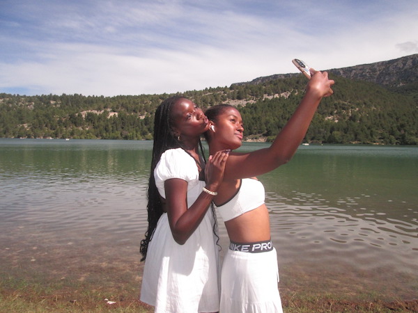 Two students taking a selfie in front of a lake.