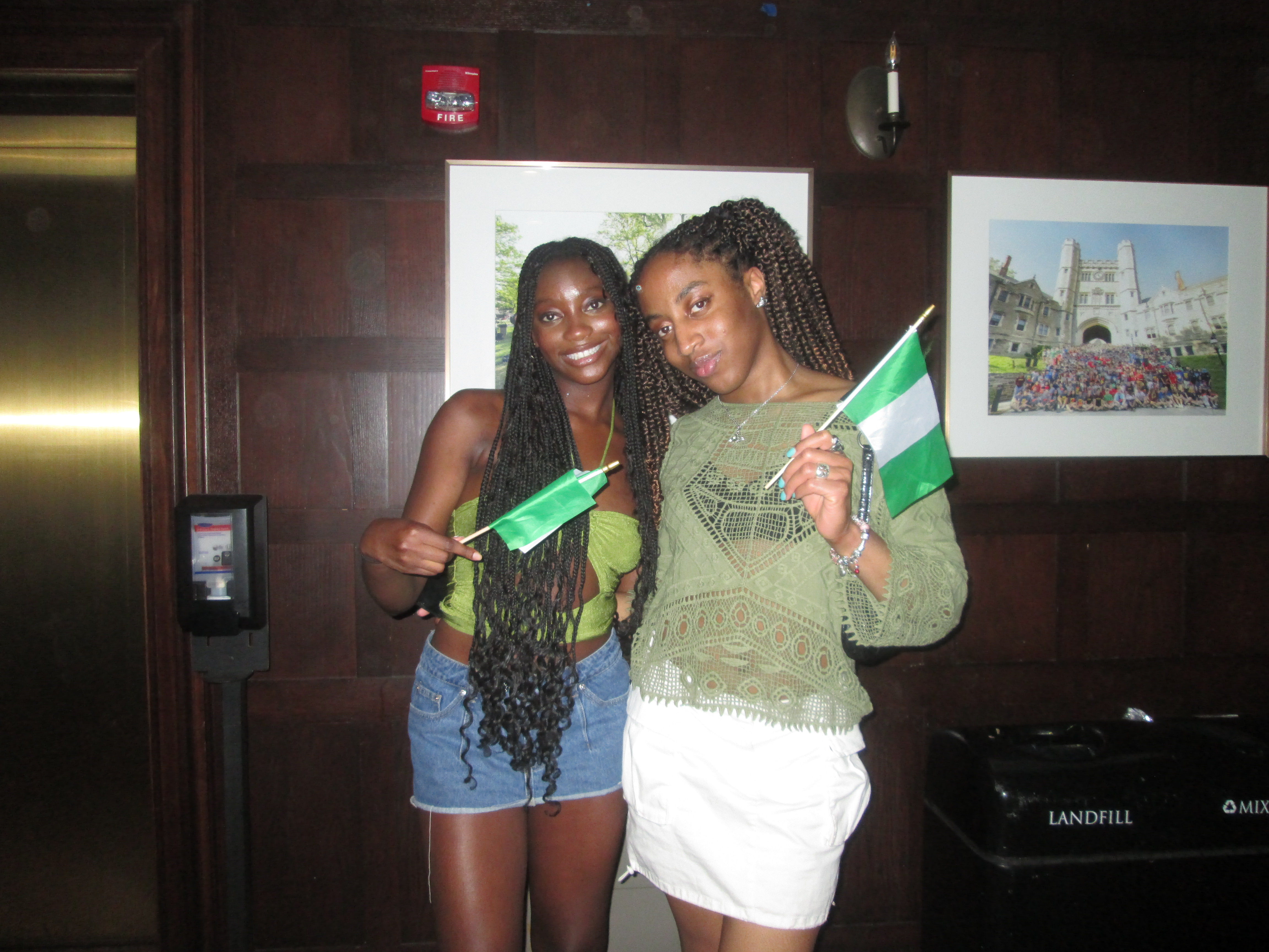 Two girls in green tops, waving Nigerian flags