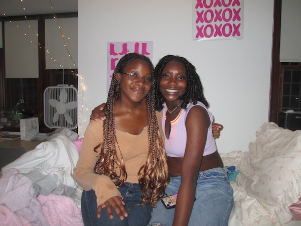 Two girls sitting on a bed in a dorm room