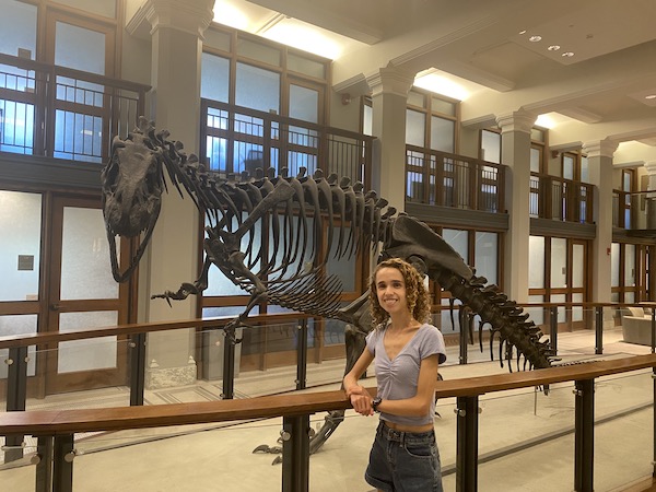 Author smiling in front of Allosaurus dinosaur skeleton in Guyot Hall