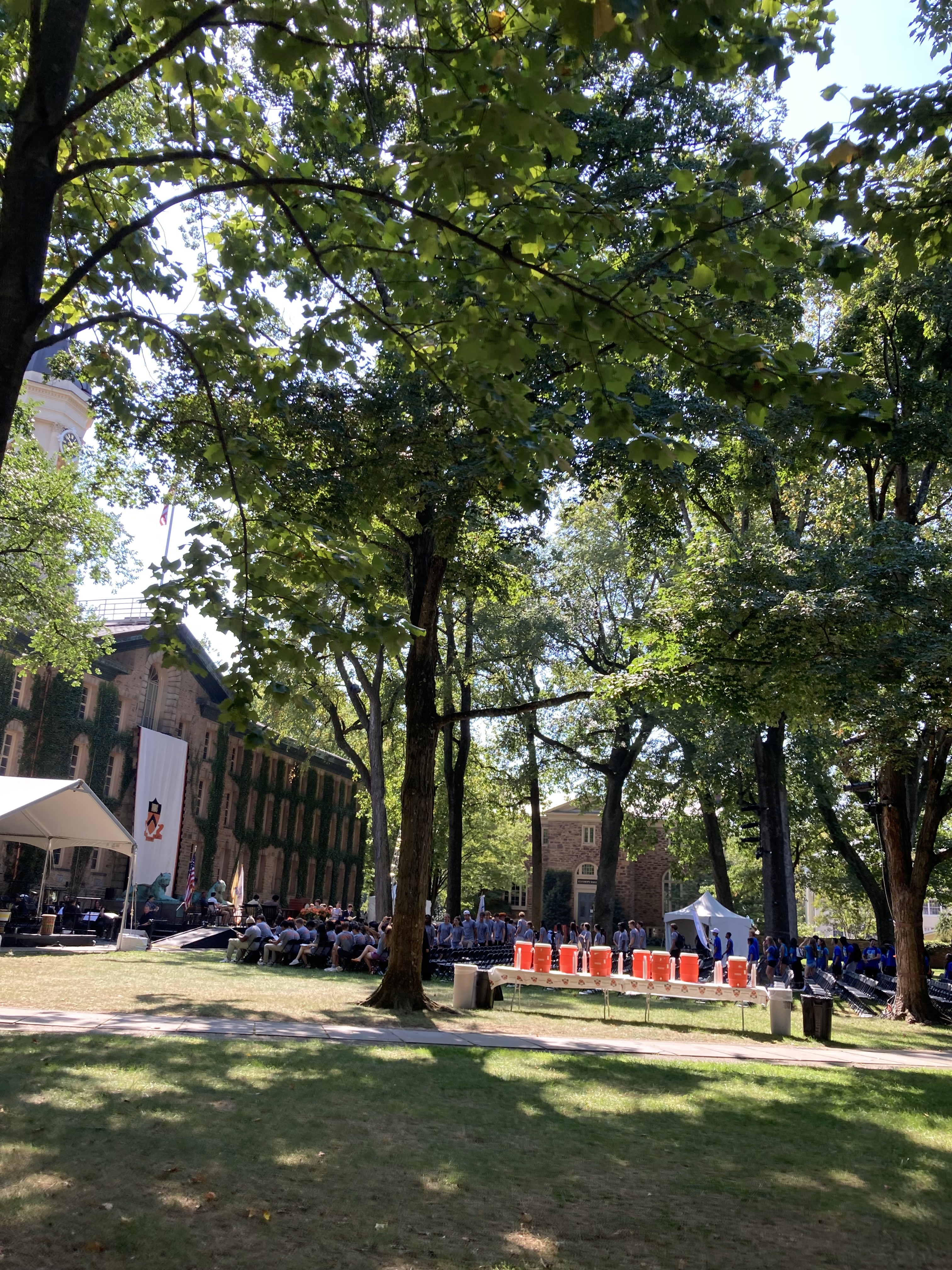 an audience of chairs faces the front of Nassau Hall, a table with water jugs is in the foreground