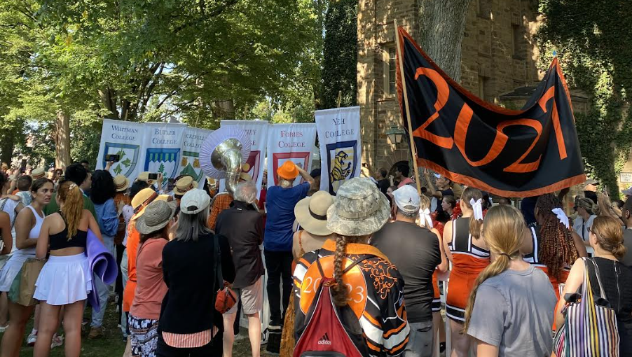 Students walking in the annual pre-rade carrying class and residential college banners.