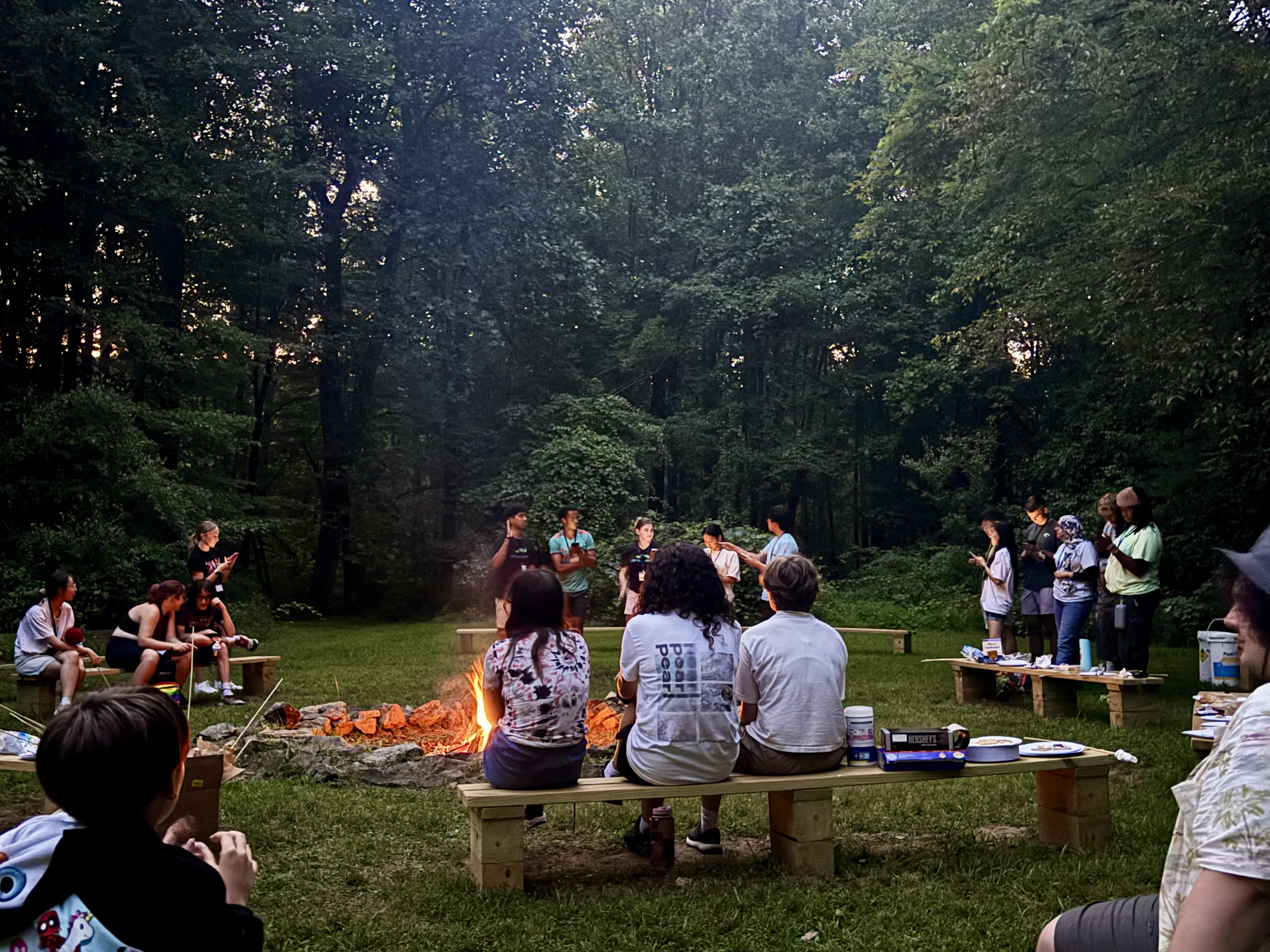 A group of kids at a campfire watching a skit performed by counselors