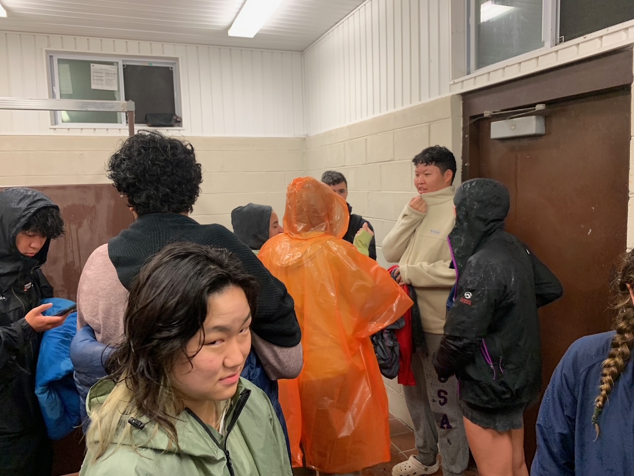 Many students wet from rain gather in a small public restroom
