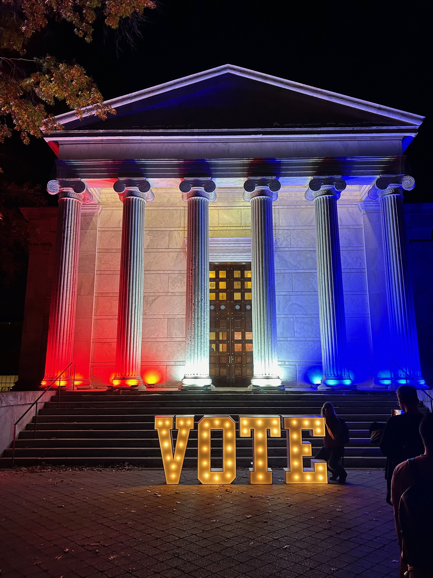 Large light up party letters spell out "VOTE" on the steps of Whig Hall