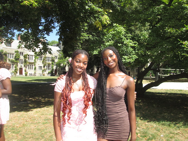 Two girls posing in front of a tree