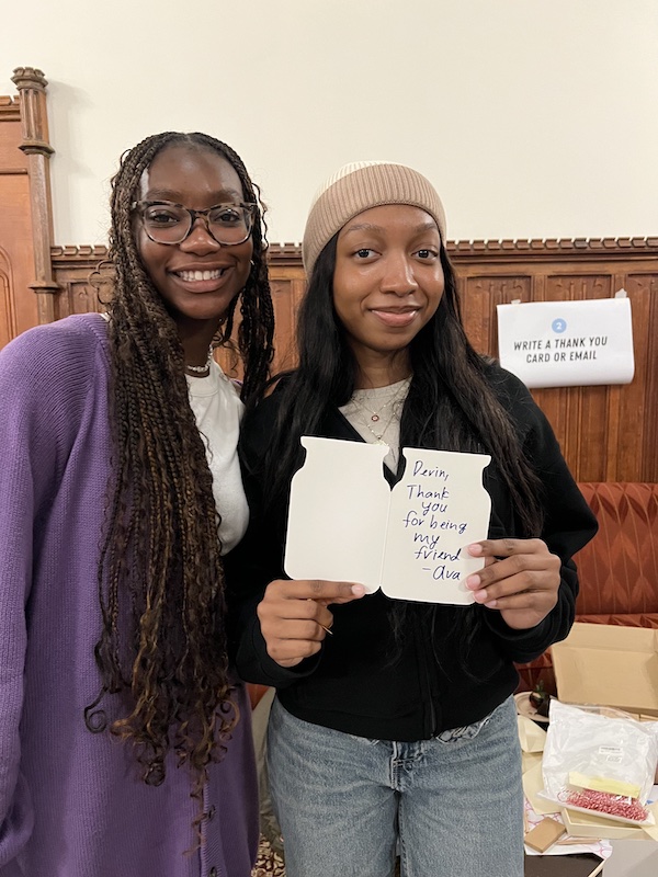 Two girls smiling; one holds a card