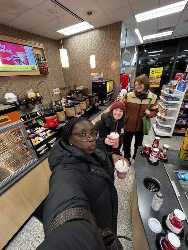 Three students posing for a selfie, holding snacks