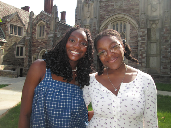 Two girls smiling in front of a rustic building
