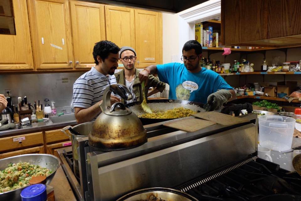 Three students cooking rice in a wok