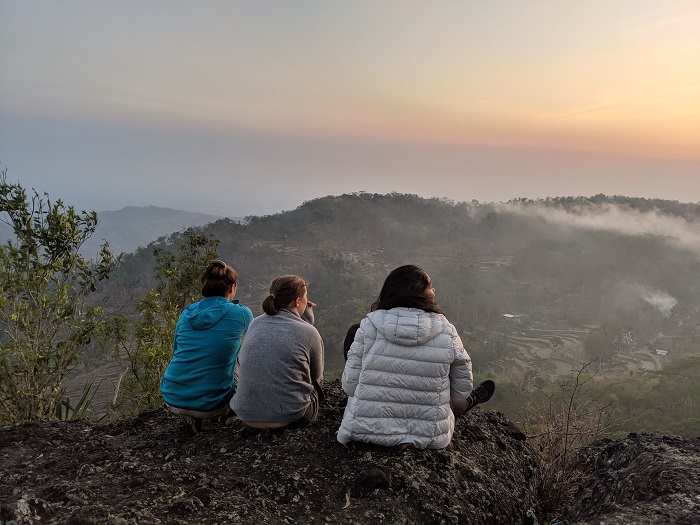 Aneekah and two other students sitting atop a mountain after a hike in Java 