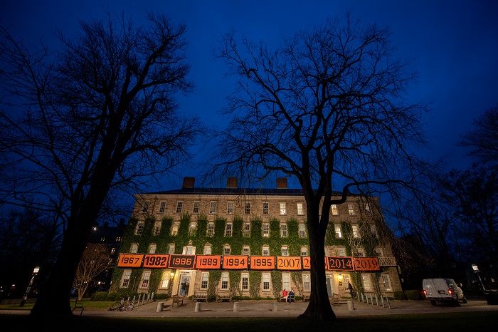 Illuminated Morrison Hall with Princeton class year banners hung on the balcony