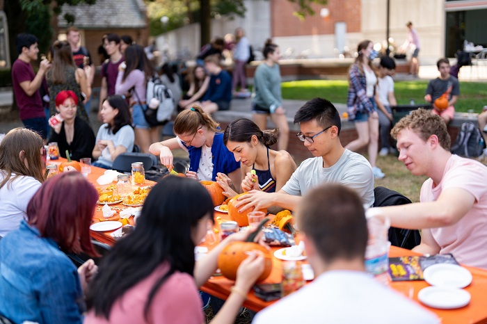 Several students sitting around a table painting small pumpkins