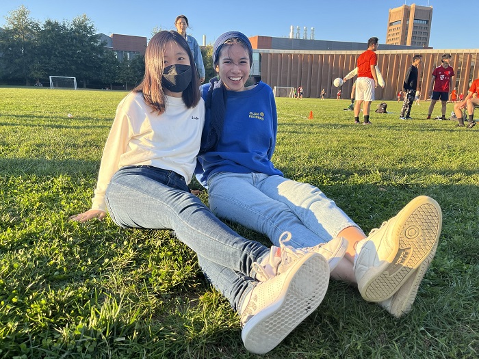 Seyi Jung sitting to the left of her friend on the soccer field