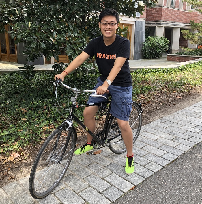 Richard on a bike in a black shirt that says Princeton in orange 