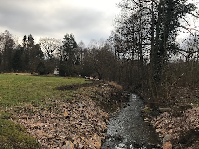 A small river with rocky banks and grass nearby