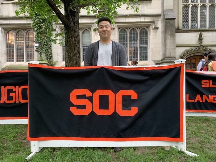 Daniel standing behind the Sociology concentration banner