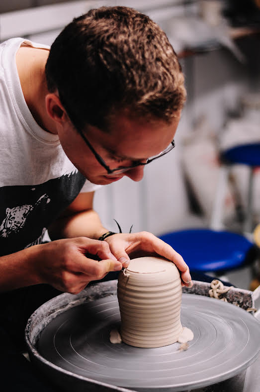 A boy carving clay on a potter's wheel