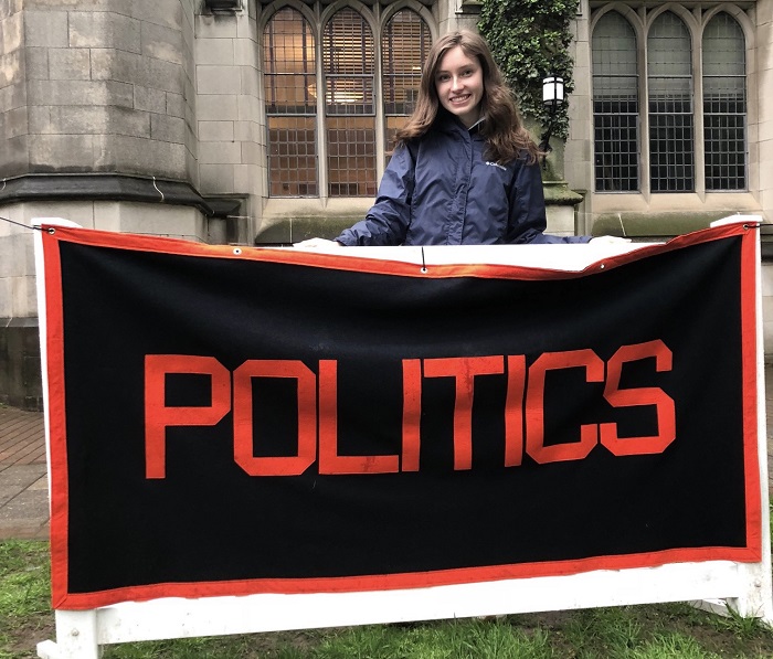 Mallory standing behind the Politics concentration banner