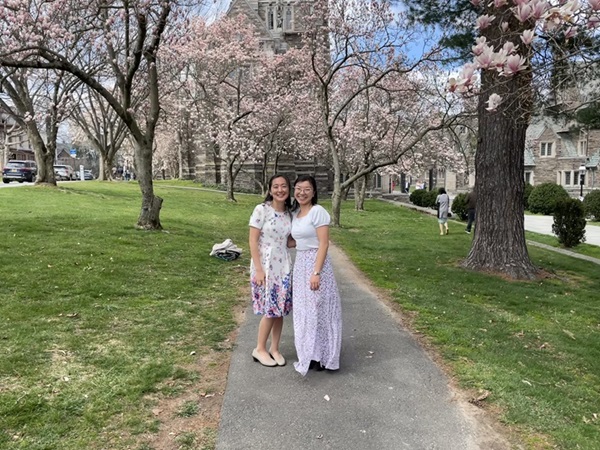My friend Grace and I standing in the middle of a walkway lined by blooming magnolia trees