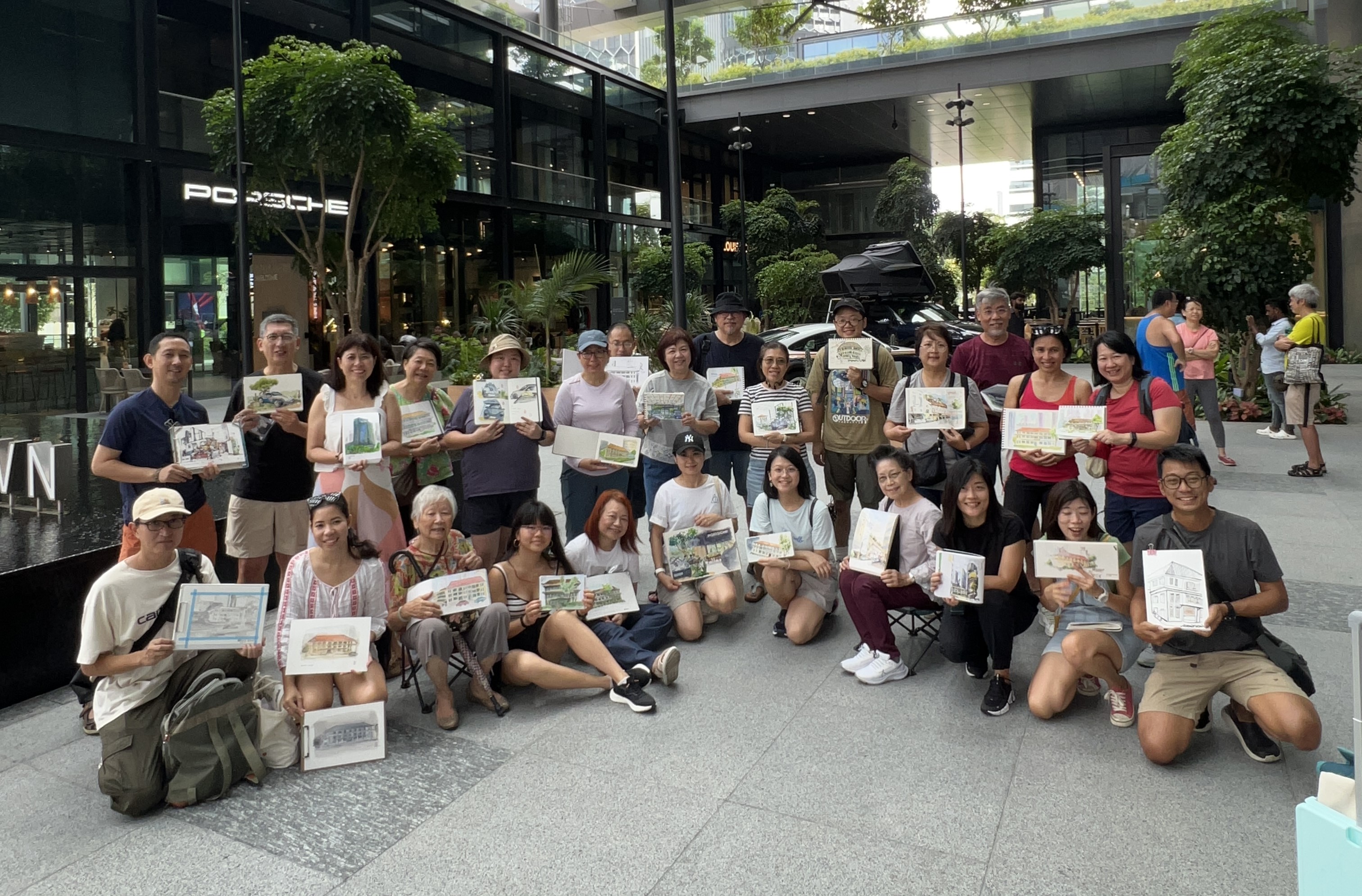 A large group people show their sketches from a sketching club meet up.