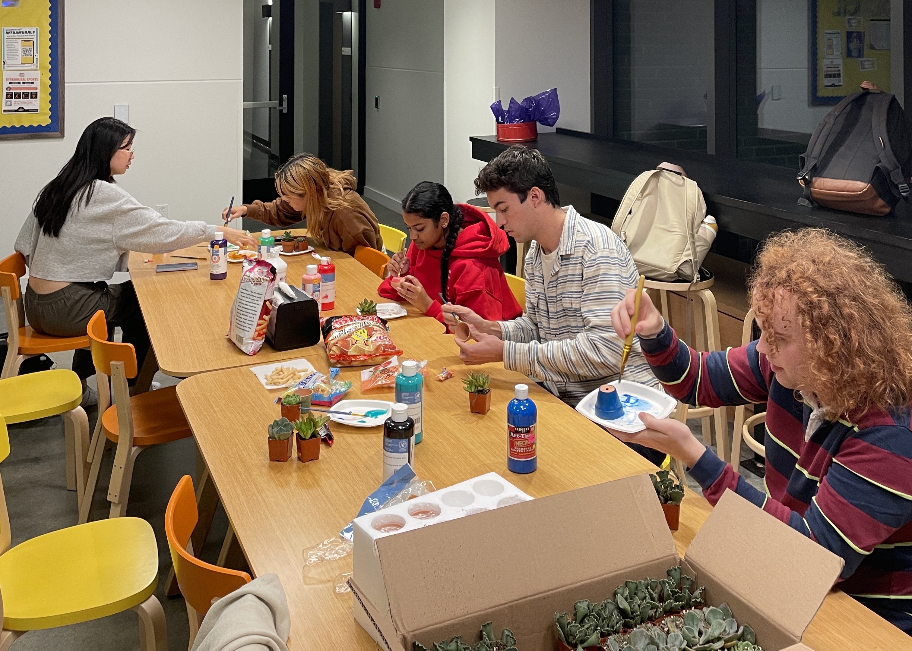 Students sit at a table painting.