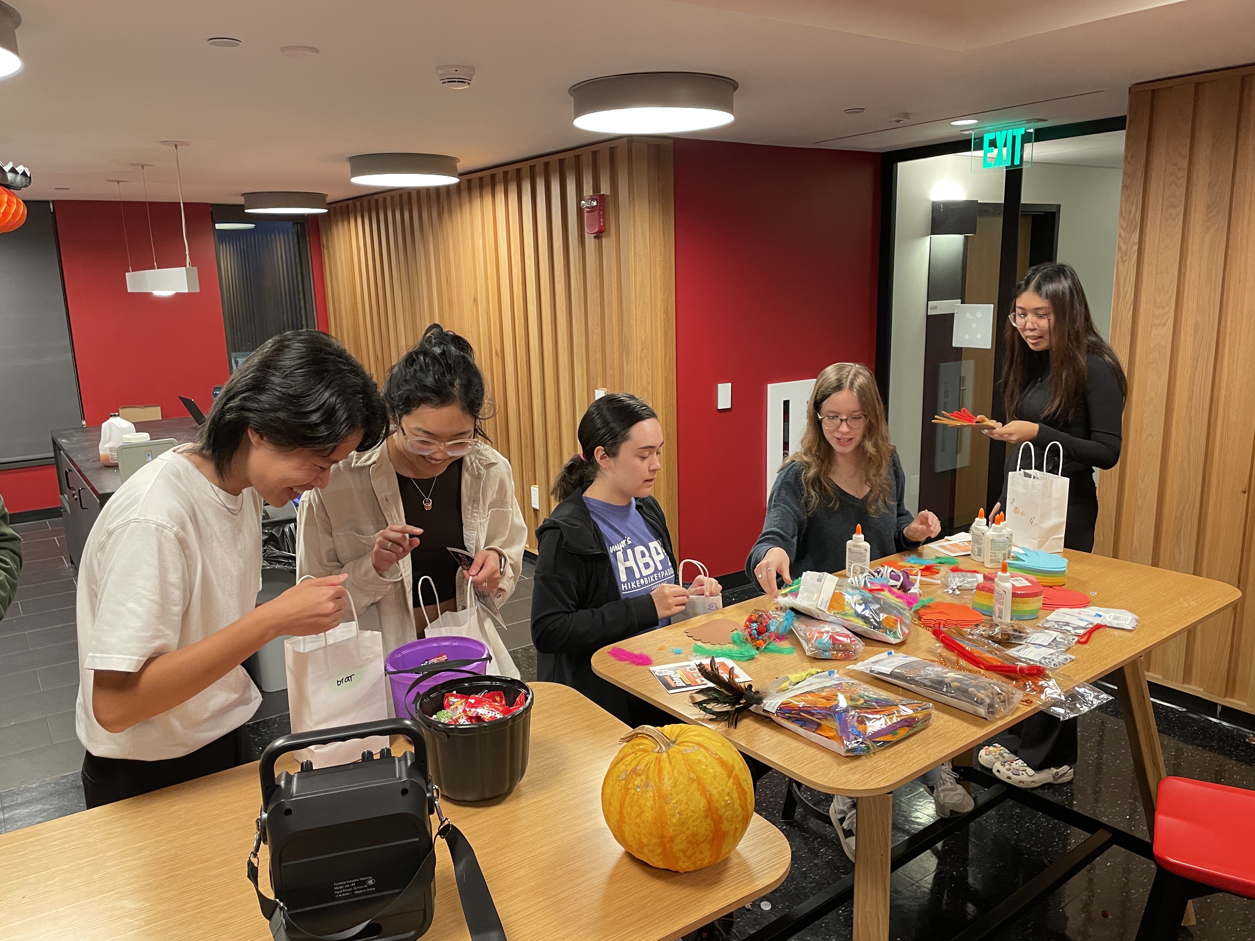 Students gather around a table covered in craft supplies.