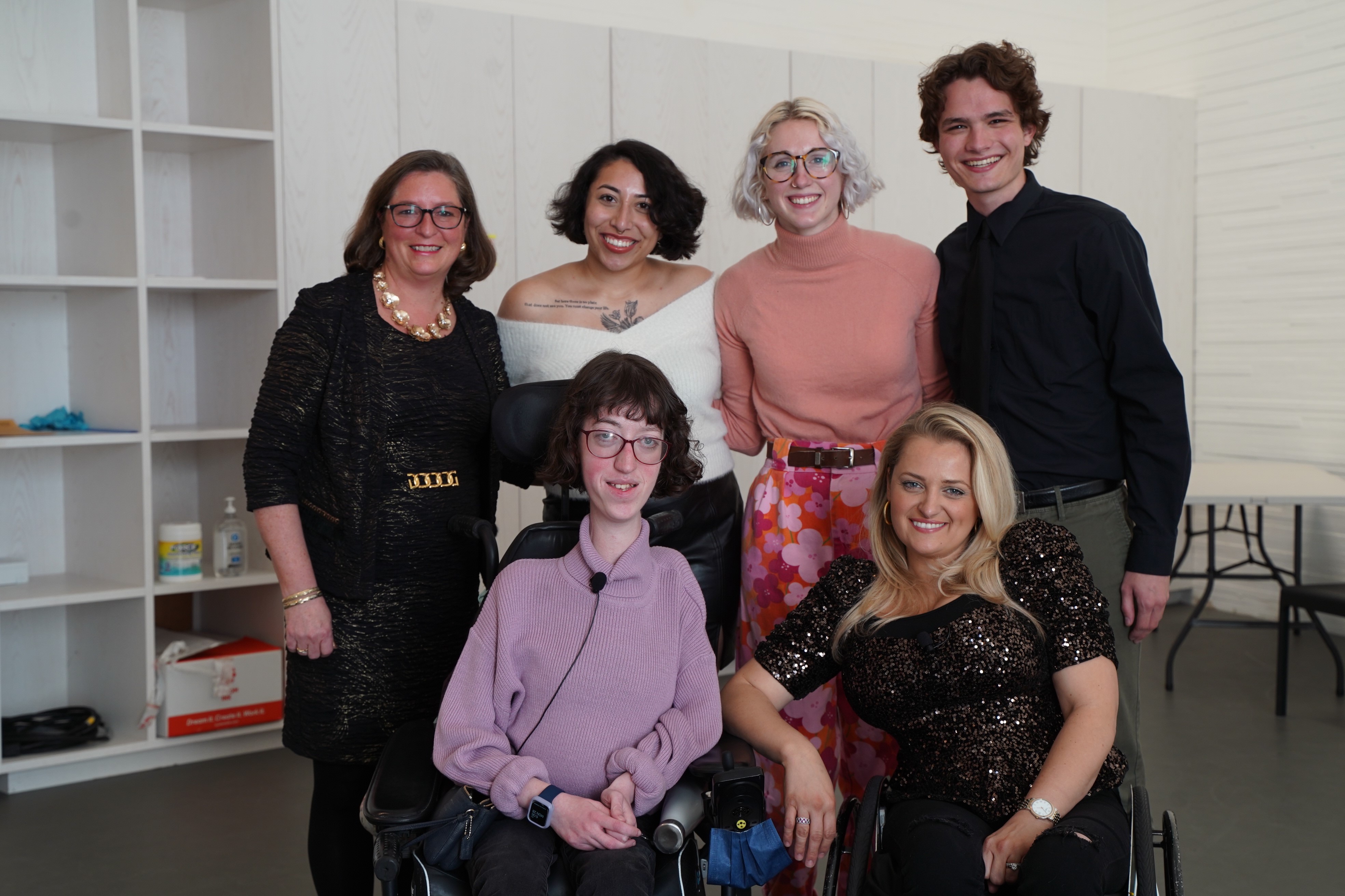 six people pose for a photo; four standing, two using wheelchairs