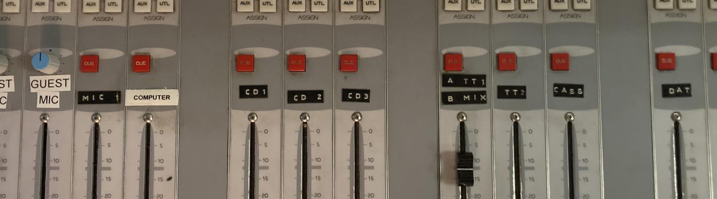 A control board in the WPRB studio, with ten channel visible. There are bright green, red and yellow lights.