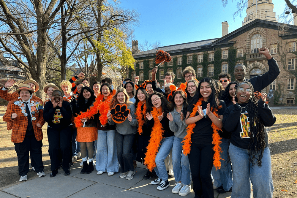Group of students in Princeton gear post cheering in front of Nassau Hall
