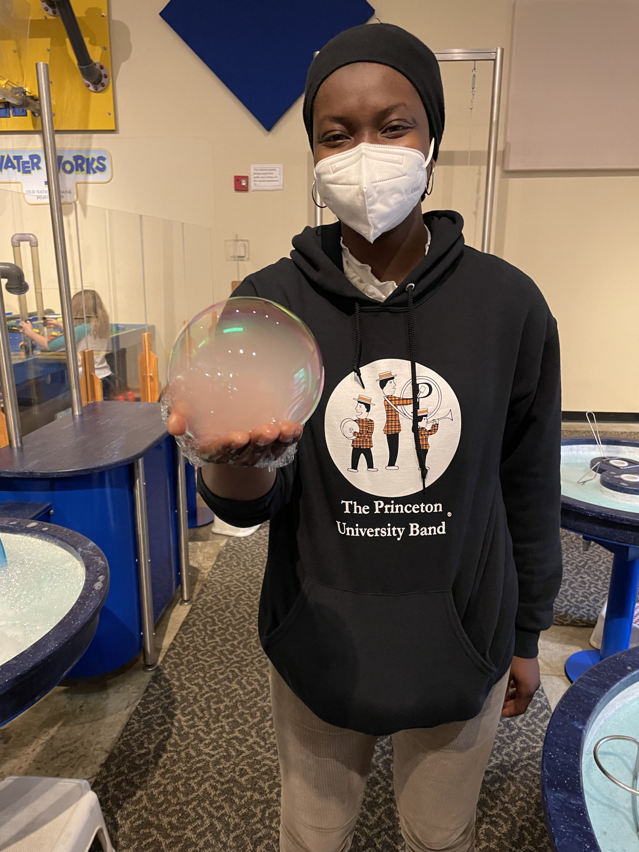 Aminah in a science museum with a "mist-filled" bubble in her hand